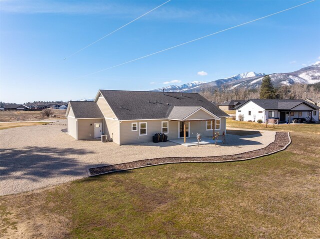 376 Cowboy Ct, Florence, MT 59833 - rear view of house with gravel driveway, a patio, a mountain view, and a lawn