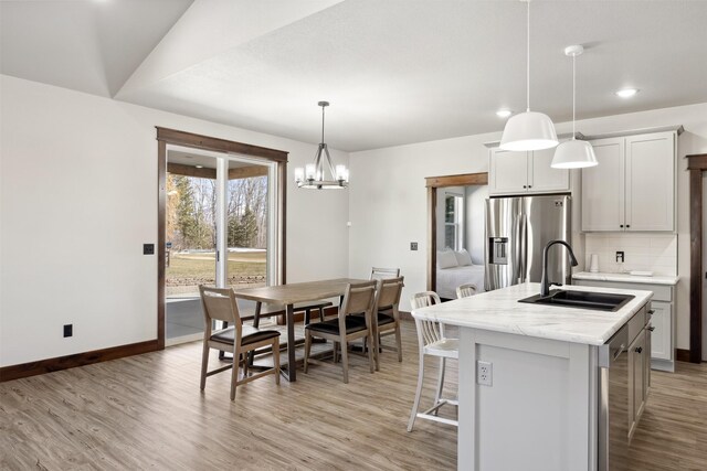 376 Cowboy Ct, Florence, MT 59833 - kitchen featuring stainless steel fridge with ice dispenser, a kitchen island with sink, light wood-type flooring, a kitchen bar, and tasteful backsplash