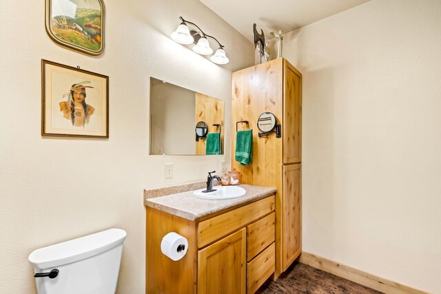 bathroom with toilet, vanity, and baseboards