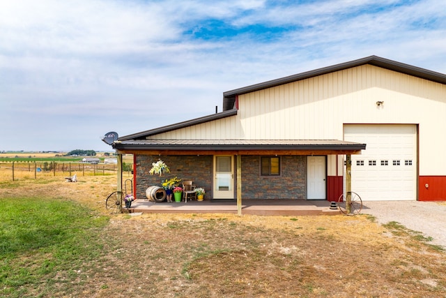 view of front of home featuring stone siding, a garage, fence, and a porch