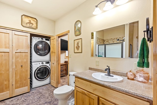 full bathroom featuring toilet, stacked washer and clothes dryer, an enclosed shower, and vanity