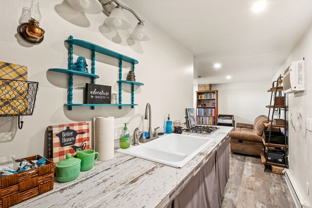 kitchen featuring light countertops, stainless steel gas cooktop, a sink, light wood-style floors, and baseboard heating
