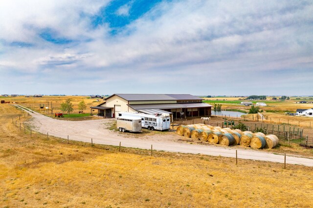 exterior space with an outbuilding, driveway, fence, and a rural view