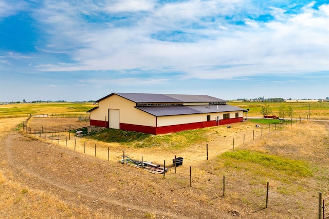 view of side of home featuring an outbuilding, fence, and a rural view