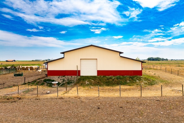view of pole building with fence and a rural view