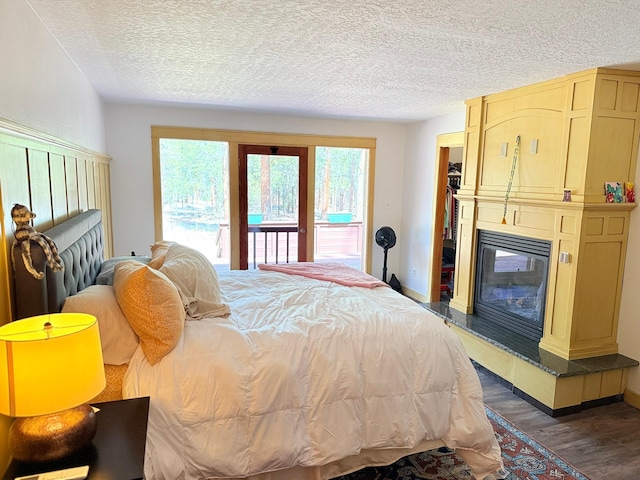 675 Bobcat Ln, Hamilton, MT 59840 - bedroom with access to outside, a fireplace, a textured ceiling, baseboards, and wood finished floors