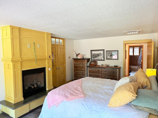 675 Bobcat Ln, Hamilton, MT 59840 - bedroom featuring a fireplace, a textured ceiling, and visible vents
