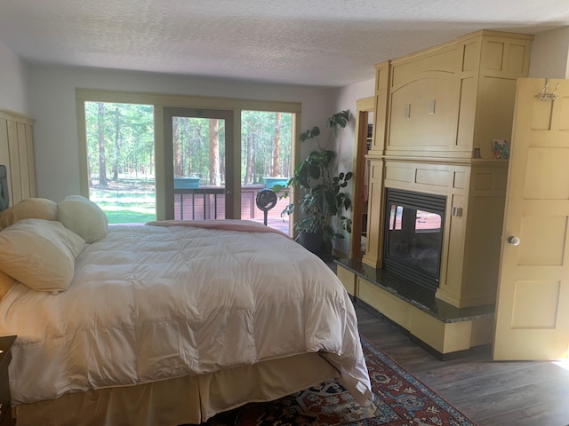675 Bobcat Ln, Hamilton, MT 59840 - bedroom with access to outside, a textured ceiling, a large fireplace, and wood finished floors