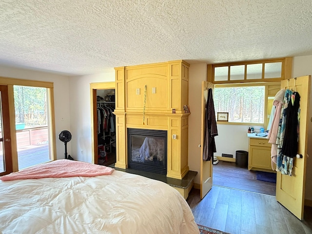 675 Bobcat Ln, Hamilton, MT 59840 - bedroom featuring wood-type flooring, a closet, a glass covered fireplace, a walk in closet, and a textured ceiling