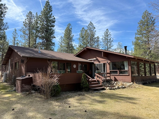 675 Bobcat Ln, Hamilton, MT 59840 - view of front of home featuring roof with shingles, a wooden deck, a sunroom, and a front lawn