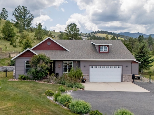 24 Sidewinder Loop, Clancy, MT 59634 - view of front of property featuring a shingled roof, concrete driveway, a mountain view, a garage, and brick siding