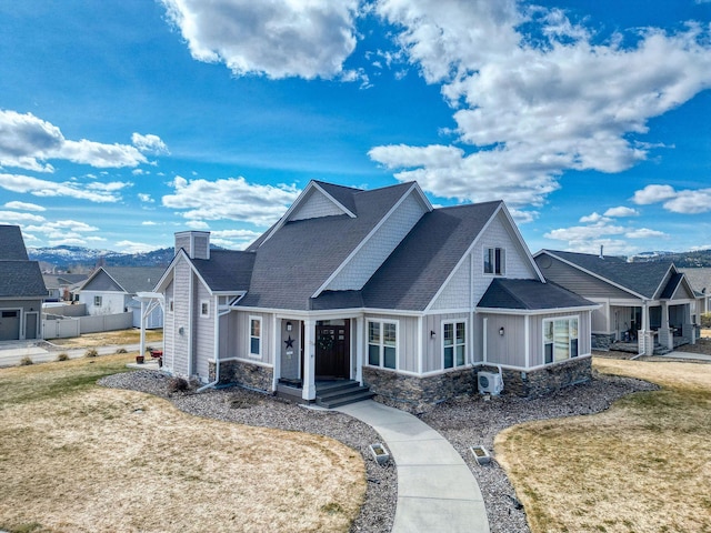 view of front of property with stone siding, roof with shingles, a chimney, board and batten siding, and a front lawn