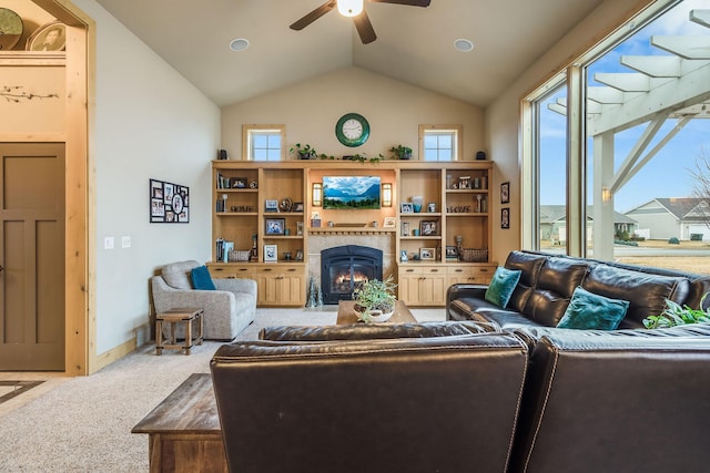 carpeted living area with baseboards, lofted ceiling, a tiled fireplace, and ceiling fan