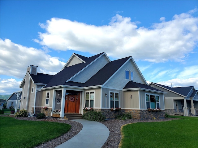 view of front of property with stone siding, board and batten siding, a front yard, and a chimney