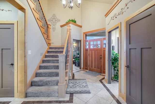 foyer featuring light tile patterned flooring, stairs, baseboards, and an inviting chandelier