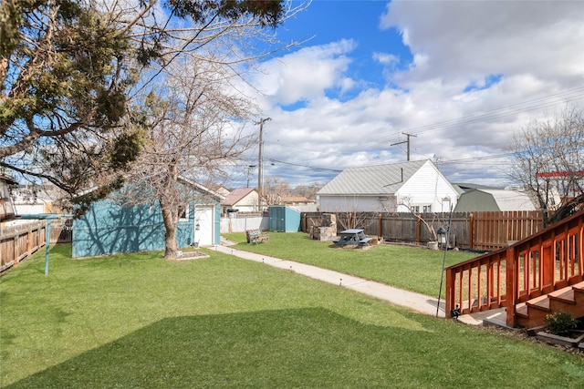 view of yard with a fenced backyard, an outbuilding, and a storage unit