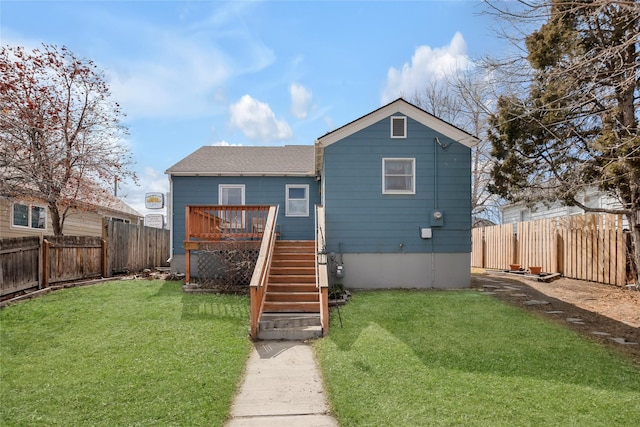 rear view of property with a fenced backyard, stairway, and a lawn