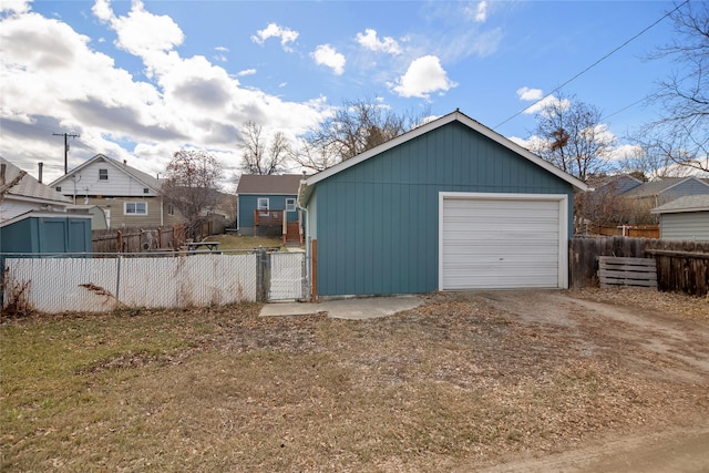 detached garage with fence and dirt driveway