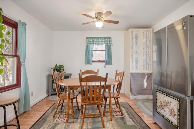 dining area with baseboards, ceiling fan, and light wood-style floors
