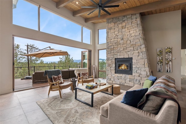 280 Cowgirl Cv, Eureka, MT 59917 - tiled living room with wooden ceiling, beam ceiling, ceiling fan, an outdoor stone fireplace, and a towering ceiling