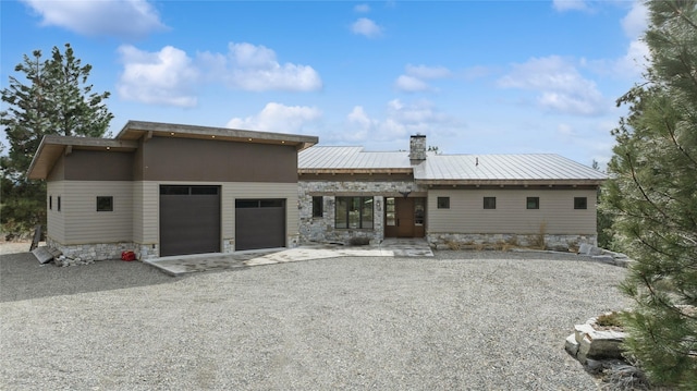 280 Cowgirl Cv, Eureka, MT 59917 - rear view of property featuring a chimney, gravel driveway, a garage, and stone siding