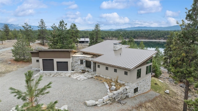 280 Cowgirl Cv, Eureka, MT 59917 - view of front of property featuring stone siding, driveway, a mountain view, a garage, and a chimney