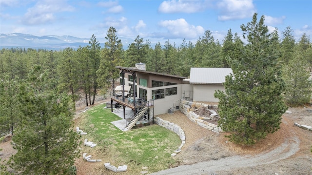 280 Cowgirl Cv, Eureka, MT 59917 - exterior space with stairs, a lawn, metal roof, a deck with mountain view, and a chimney