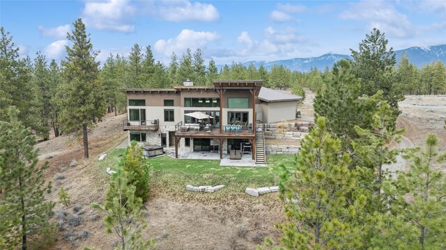 280 Cowgirl Cv, Eureka, MT 59917 - rear view of house with stairway, a patio, stone siding, a deck with mountain view, and a lawn