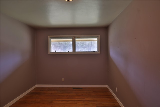 empty room with visible vents, baseboards, and wood finished floors