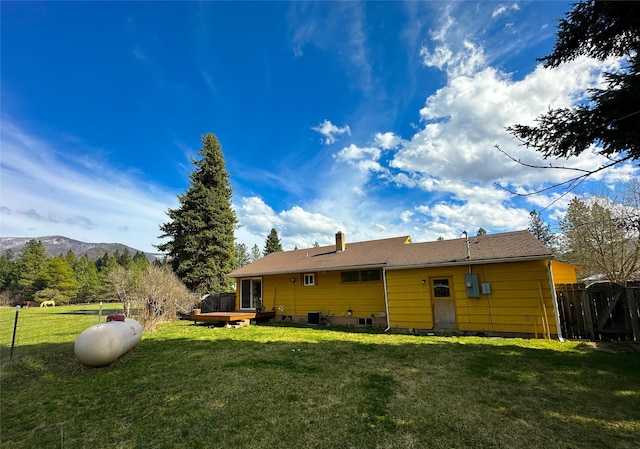 back of property featuring a yard, a chimney, fence, and a deck with mountain view