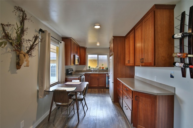 kitchen with brown cabinetry, wood finished floors, and appliances with stainless steel finishes