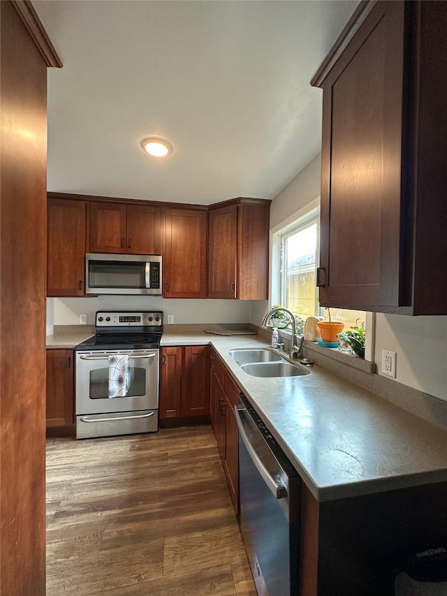 kitchen with light countertops, a sink, stainless steel appliances, and dark wood-style floors