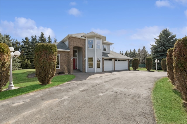 view of front of home featuring a front yard, roof with shingles, concrete driveway, brick siding, and a garage
