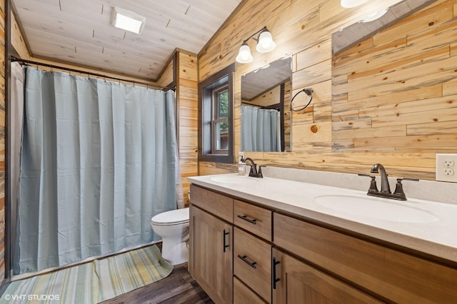 bathroom featuring double vanity, wooden walls, toilet, and a sink