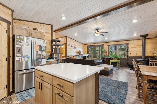kitchen with wooden walls, ceiling fan, open floor plan, a wood stove, and freestanding refrigerator
