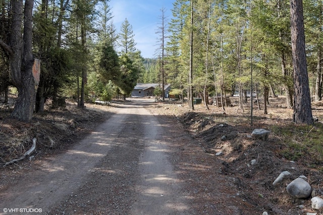 view of street with driveway and a view of trees