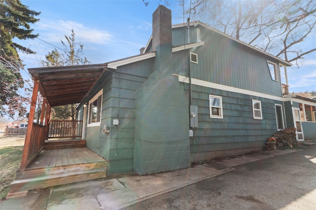 602 16th Ave E, Polson, MT 59860 - view of side of property featuring a chimney, a porch, and concrete block siding