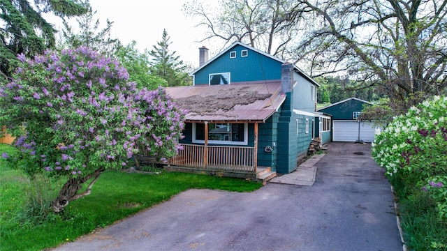 602 16th Ave E, Polson, MT 59860 - view of front of home with a detached garage, covered porch, an outdoor structure, a chimney, and metal roof