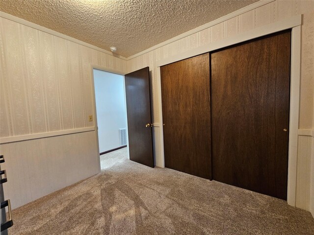 308 Dakota Ave, Libby, MT 59923 - unfurnished bedroom featuring ornamental molding, carpet, a textured ceiling, visible vents, and a closet