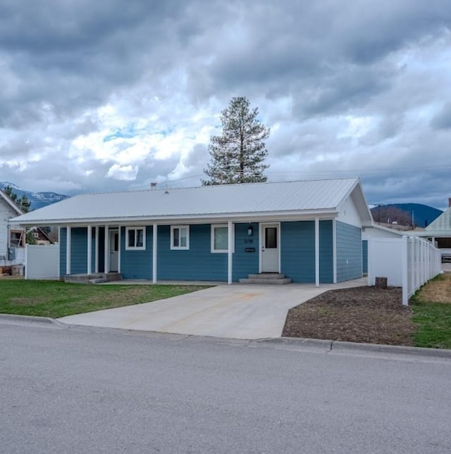 308 Dakota Ave, Libby, MT 59923 - ranch-style home with a front yard, concrete driveway, fence, and metal roof