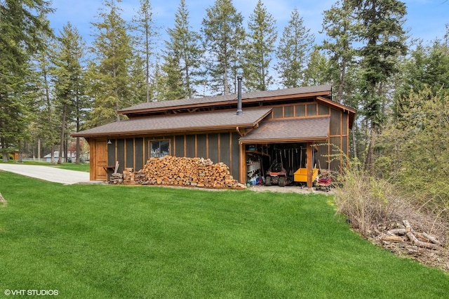 rear view of property with a yard, a sunroom, an attached garage, and roof with shingles