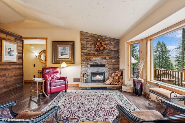 living area featuring lofted ceiling, wood finished floors, baseboards, and a fireplace