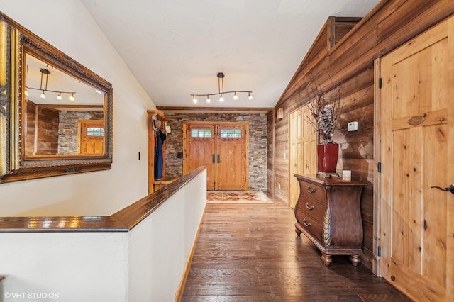 hallway featuring rail lighting, wood-type flooring, and wooden walls