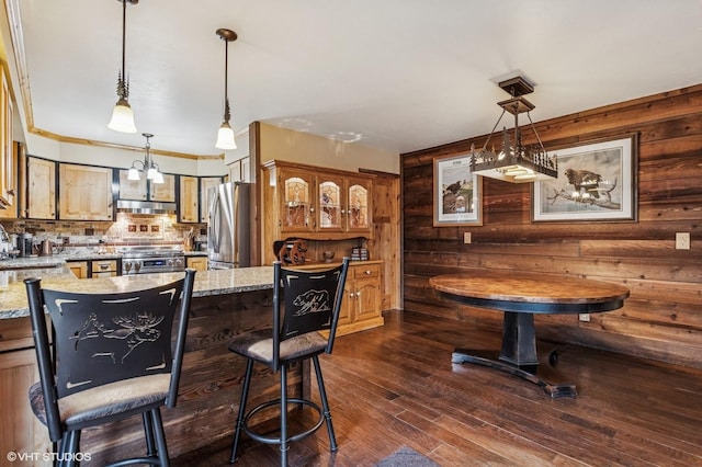 bar featuring appliances with stainless steel finishes, tasteful backsplash, dark wood-style floors, pendant lighting, and under cabinet range hood