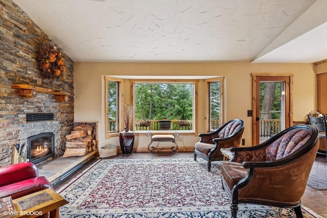 living area with a stone fireplace, baseboards, and wood finished floors