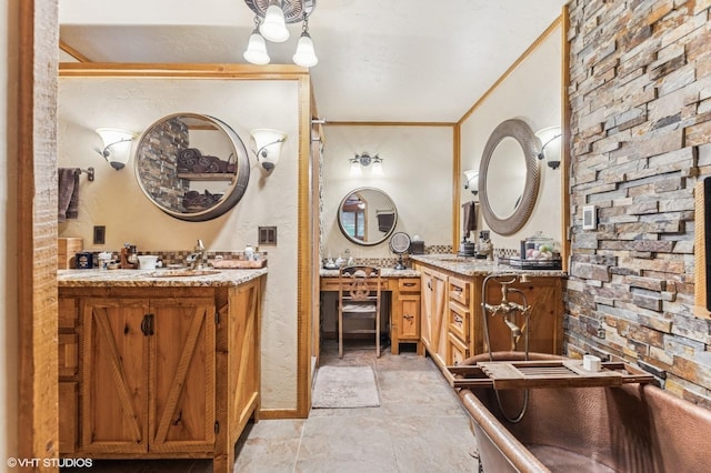full bathroom featuring two vanities, stone finish floors, and ornamental molding