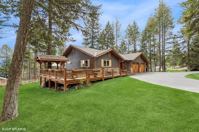 back of property featuring driveway, a yard, an attached garage, and a wooden deck