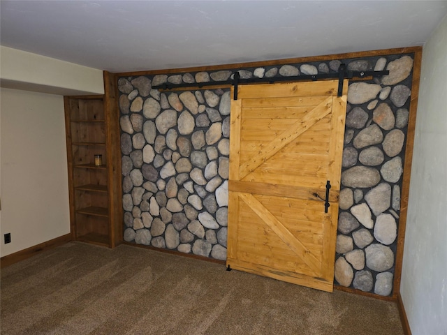 unfurnished room featuring carpet floors, baseboards, and a barn door