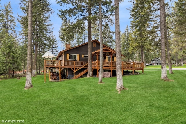 rear view of house featuring a chimney, a deck, and a lawn