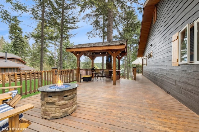 wooden terrace with an outdoor fire pit, outdoor dining area, and a gazebo